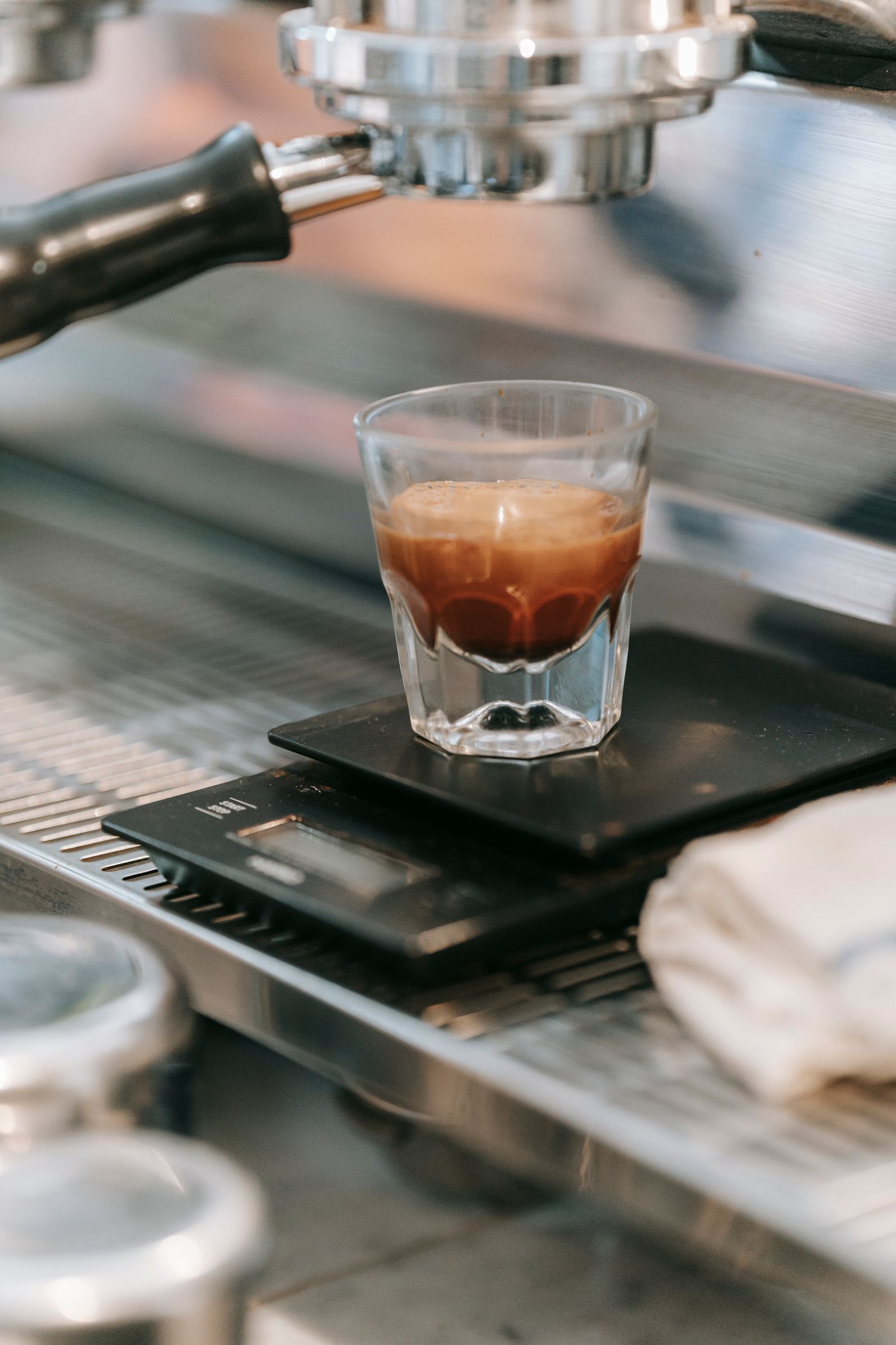 An espresso shot being pulled on a scale under a portafilter