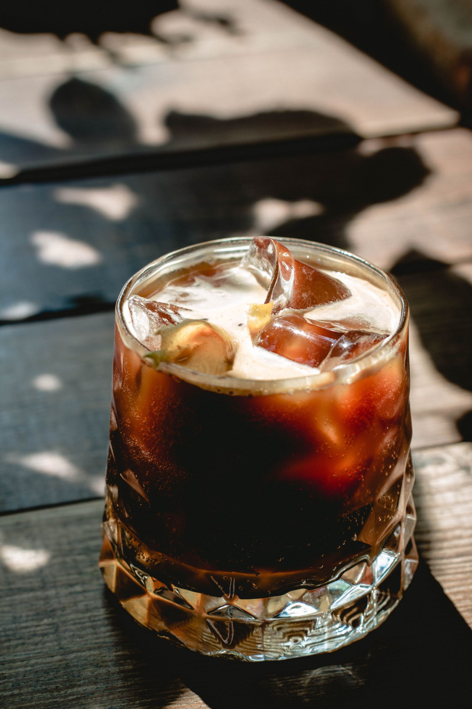 Iced coffee with crema in a cut-crystal glass on a wooden table